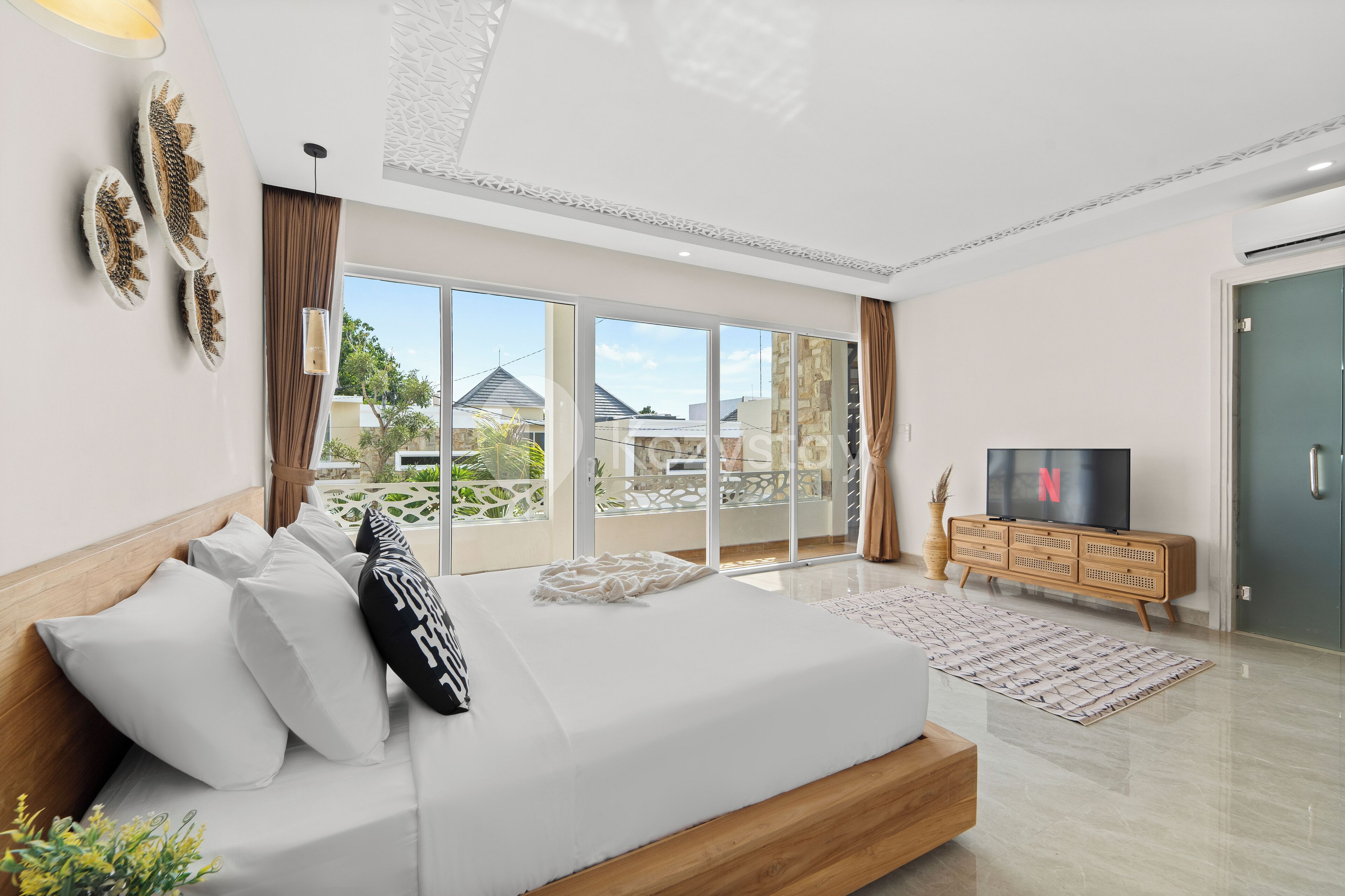 Ett modernt sovrum med en stor säng, en tv och utsikt över ett bostadsområde.