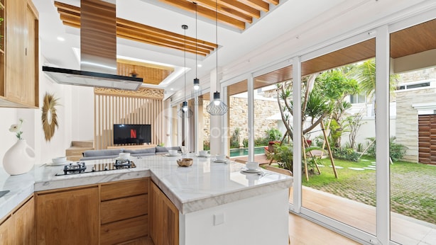 Una cocina moderna con una isla grande, armarios de madera y una estufa a gas empotrada.