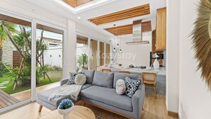 Un salón moderno con un sofá gris, techo de madera y vistas a un jardín.