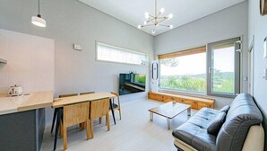 A modern living room with a sofa, a dining table, and a TV. - Chuncheon Stay 266 (Chuncheon)