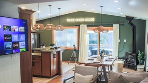 A modern kitchen with a TV displaying streaming services, a dining area with a table set for four, and a cozy living room with a sofa and a fireplace. - 4 BR Retreat with Lakeview and Hot Tub (Kings Beach)