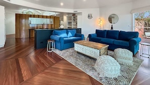 A spacious living area with two blue sofas, a coffee table, and a patterned rug. - Spacious 4-Bed Home with Coastal Charm (Long Beach)
