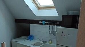 Een compacte keuken met dakraam, een spoelbak, een magnetron en een koelkast.