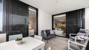 Een moderne hotelkamer met een zithoek, een zithoek en een keuken, zichtbaar door glazen deuren.