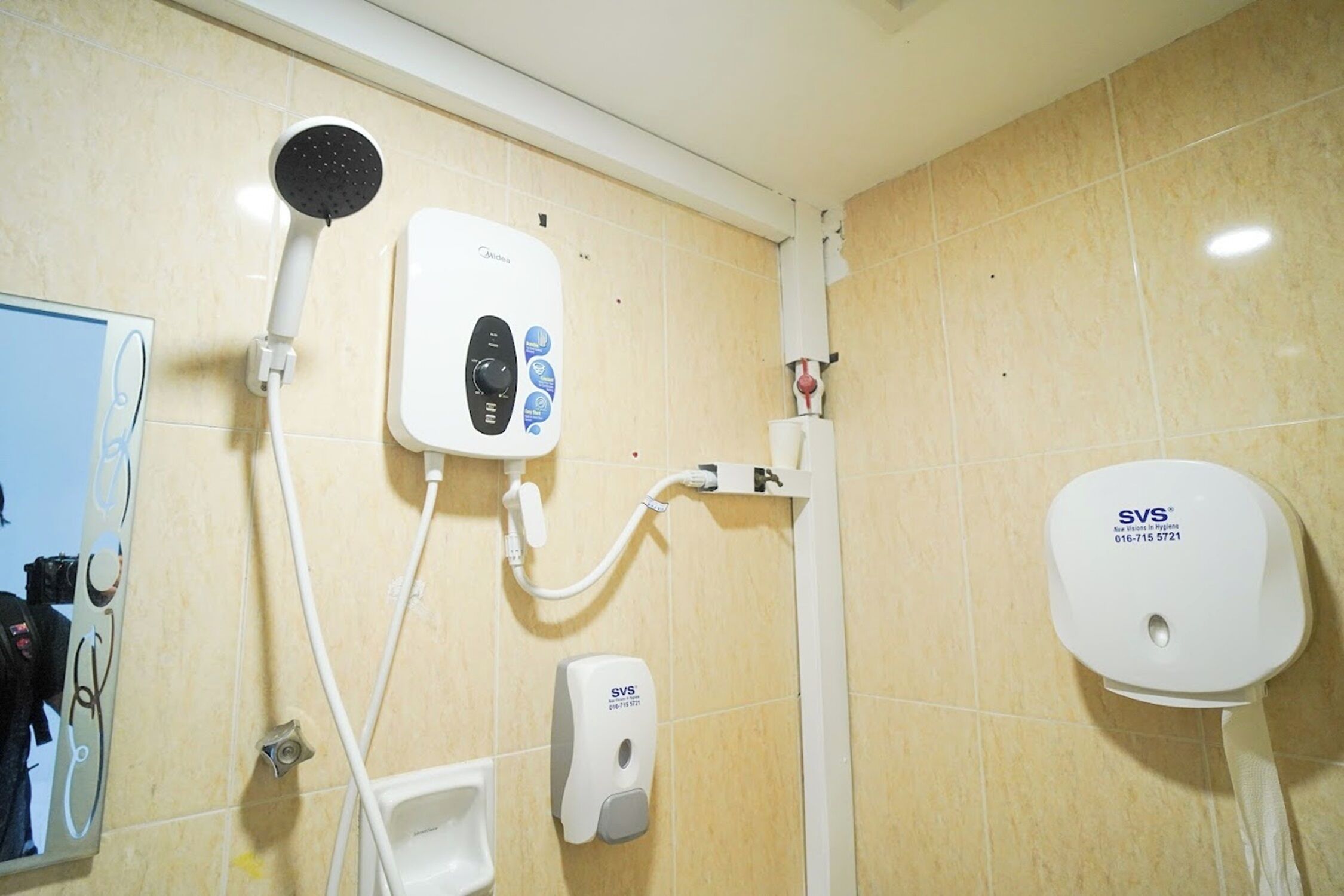 A bathroom with a shower, a hand dryer, and a soap dispenser.