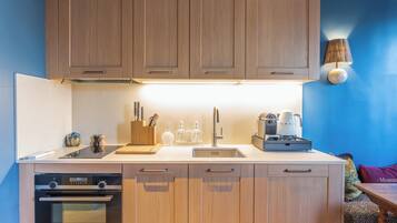 A modern kitchen with wooden cabinets, a built-in oven, and a coffee maker.