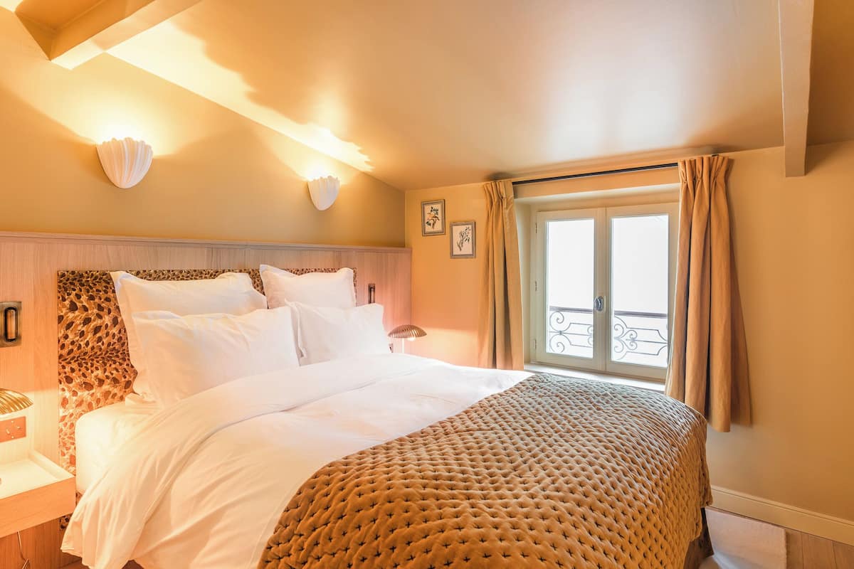 A neatly made bed with a patterned bedspread, a headboard with a leopard print design, and a wall-mounted light fixture.