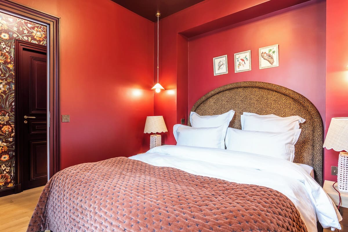 A room with a large bed, red walls, and a decorative headboard.