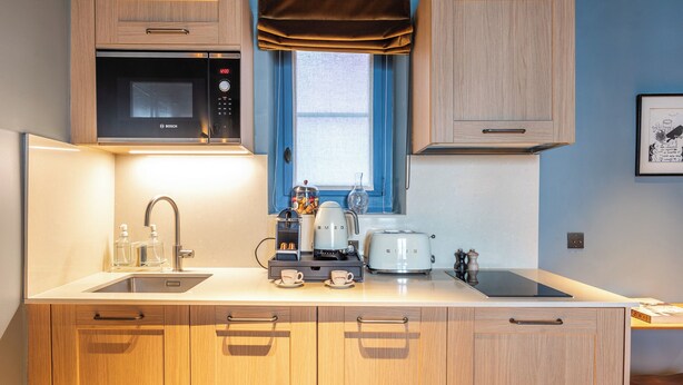 A modern kitchen with wooden cabinets, a Bosch microwave, a coffee maker, and a toaster. - Maison La Bohème Montmartre - Studios & Apartments (Paris)