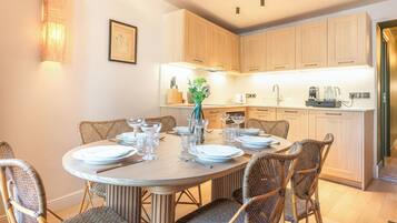 A dining area with a round table set for six, surrounded by wicker chairs.
