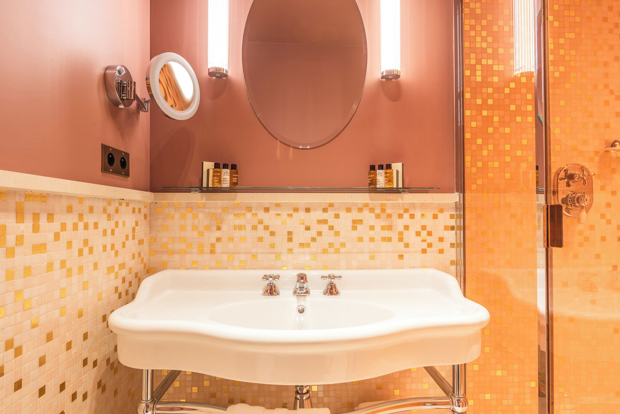Ein Badezimmer mit einem weißen Waschbecken, einem Spiegel und einer Dusche mit Glastür.