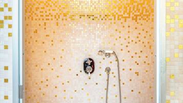 A shower with mosaic tile walls and a handheld showerhead.
