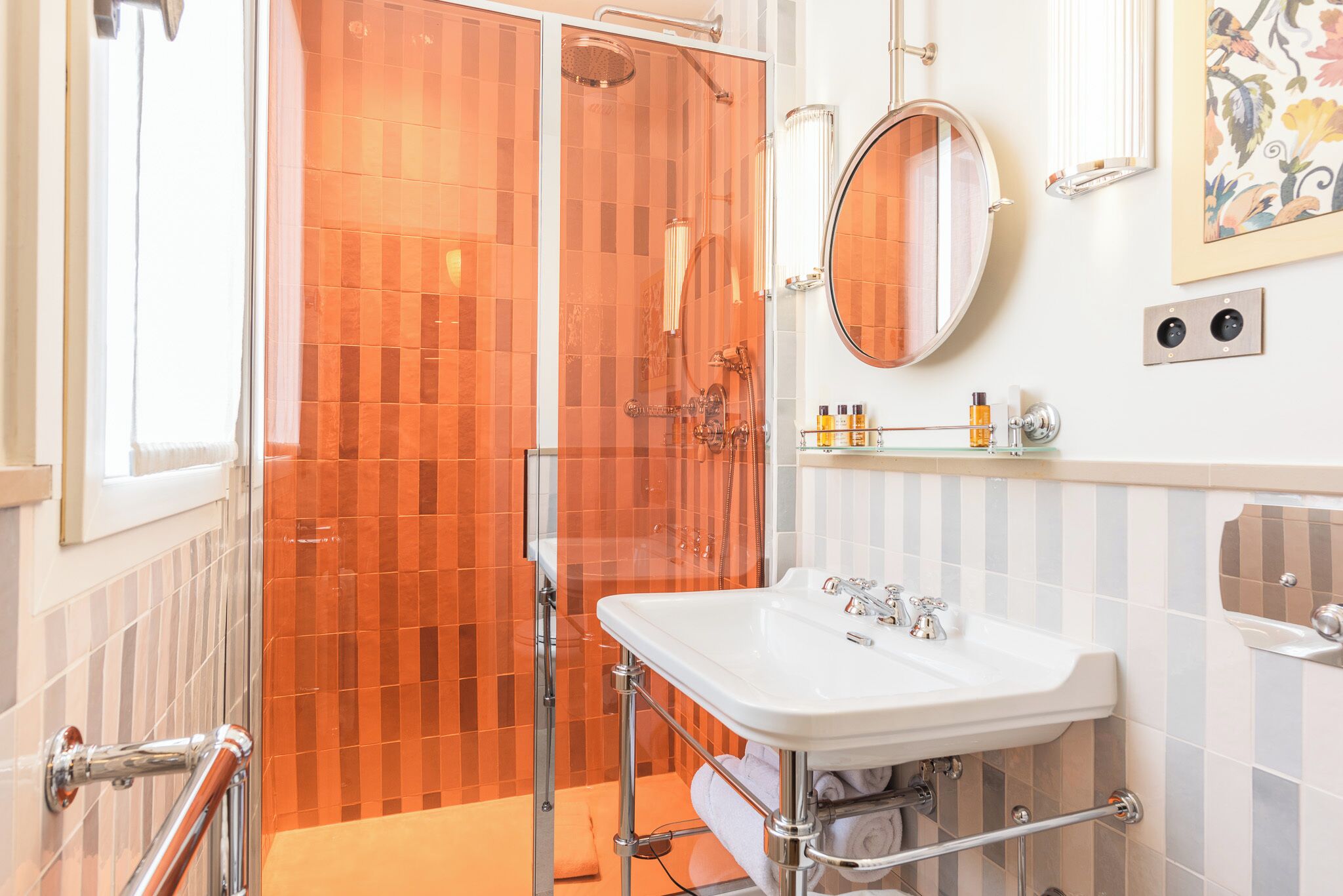 A bathroom with a glass-enclosed shower, a white sink, and a mirror above it.