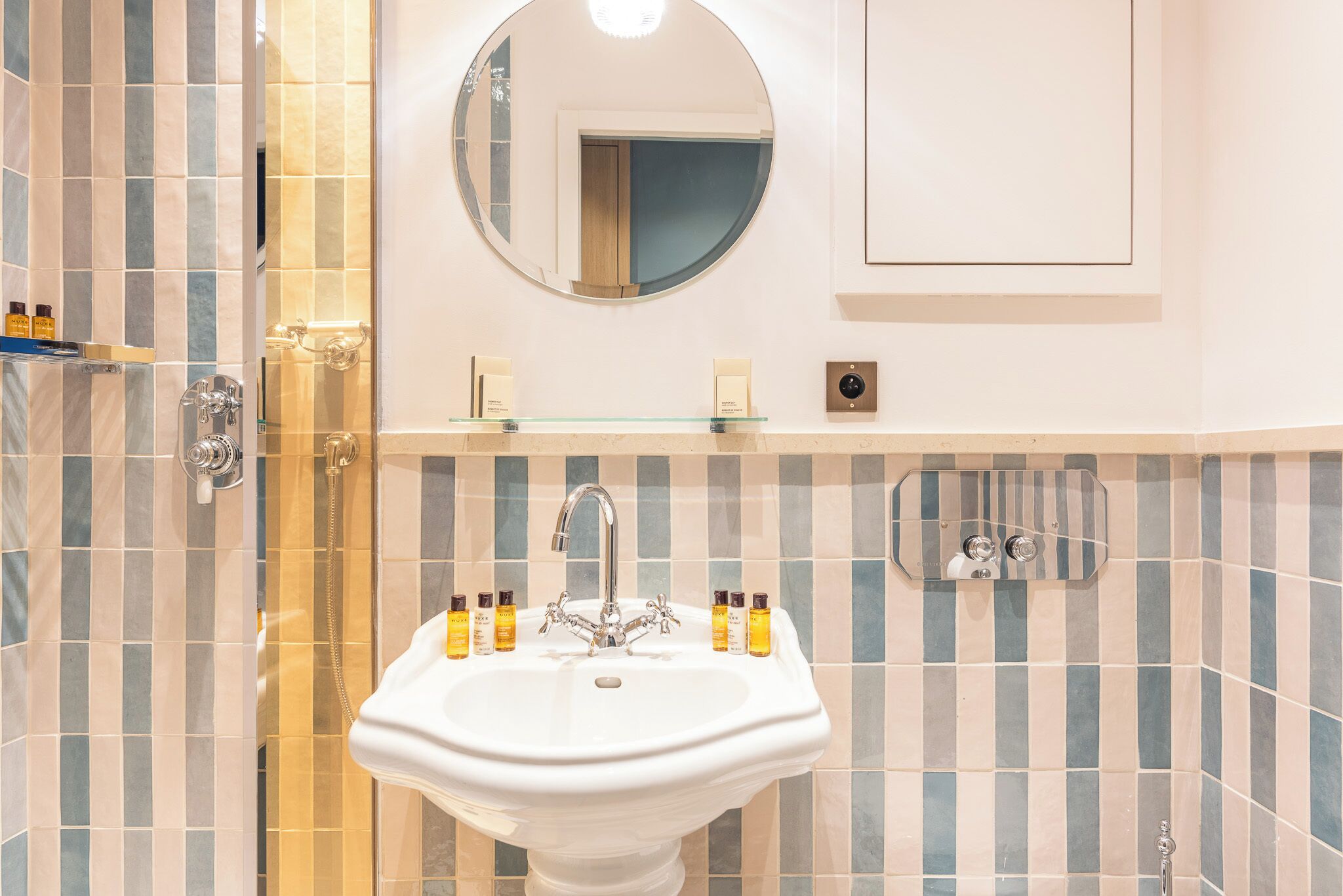 A bathroom with a white sink, a round mirror, and a shower area.