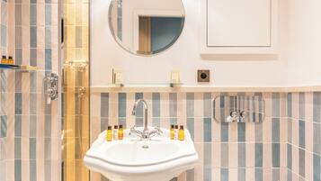 A bathroom with a white sink, a round mirror, and a shower area.