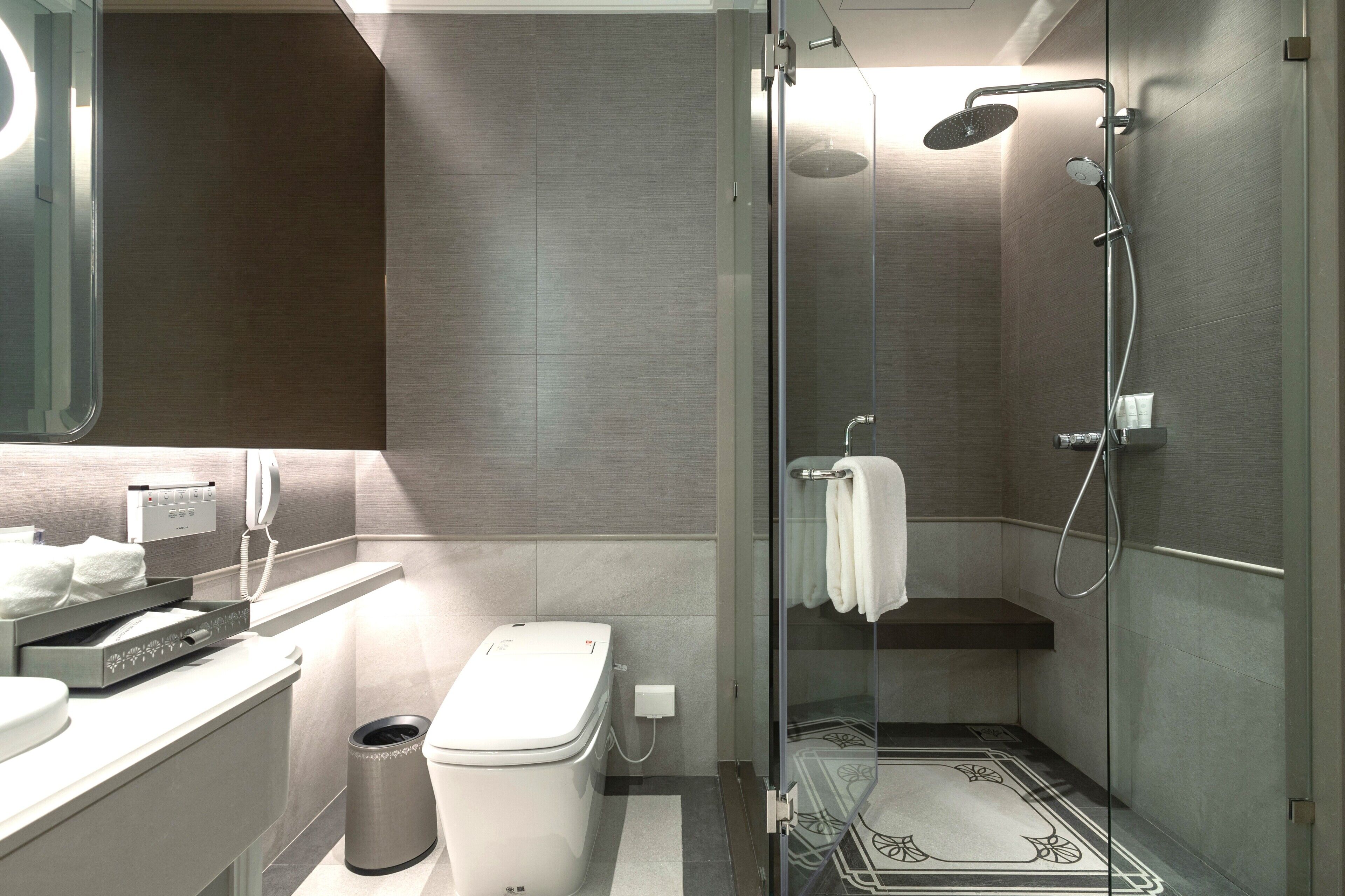 A modern bathroom with a glass-enclosed shower, a toilet, and a vanity with a mirror.