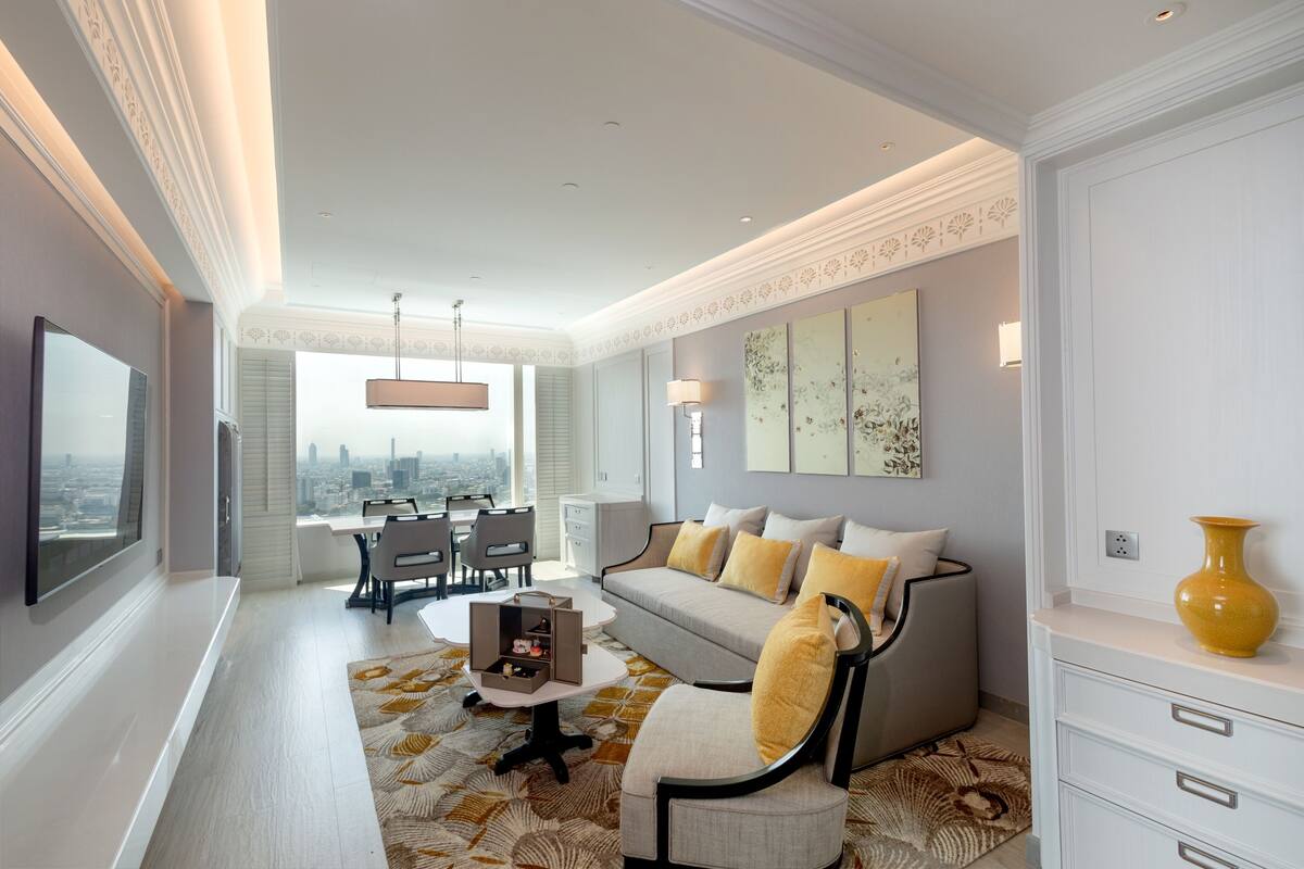 Un salon moderne comprenant un canapé, des fauteuils, une table basse et un coin repas avec une table et des chaises.