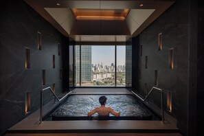 A man in a modern indoor pool with a cityscape view through large windows. - Grande Centre Point Lumphini Bangkok (Bangkok)