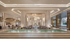 A luxurious lobby with a central fountain, elegant seating, and a grand chandelier.