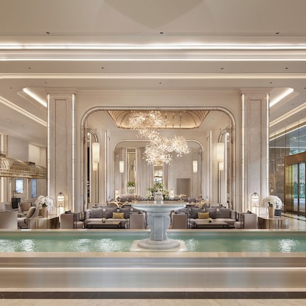 A luxurious lobby with a central fountain, elegant seating, and a grand chandelier.