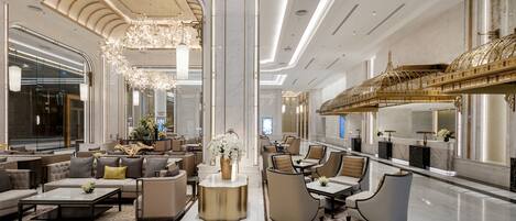 A spacious lobby with a high ceiling, elegant chandeliers, and a grand staircase.