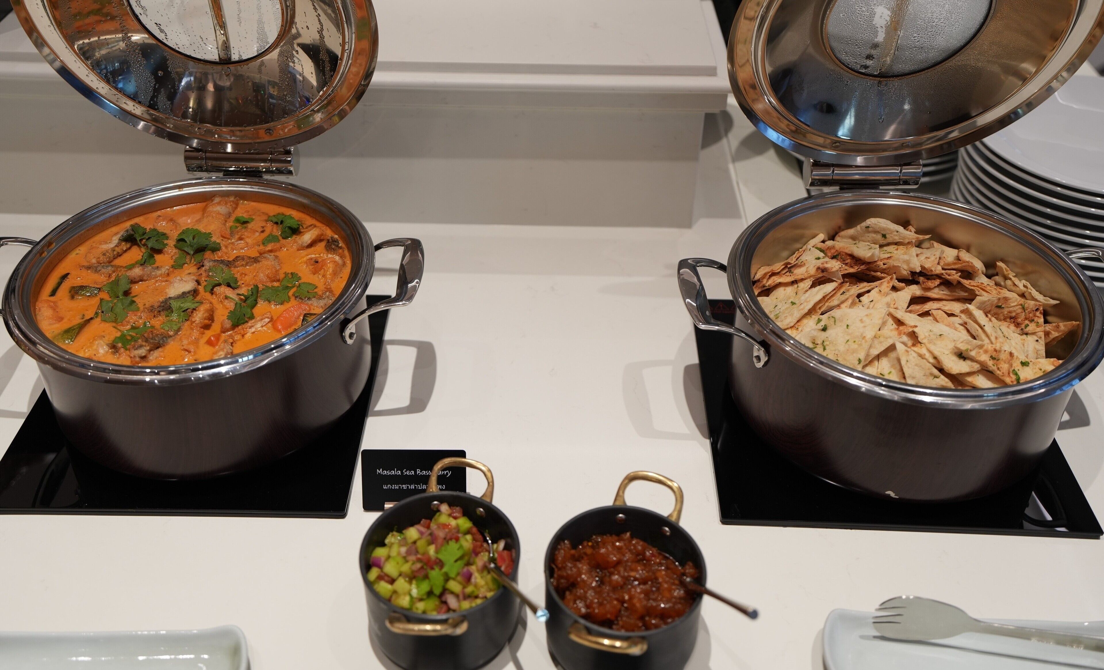 Un bufé con dos grandes ollas de curry y una olla de pan plano.