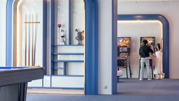 A modern interior with a pool table, a game area with arcade machines, and a seating area with a white sofa.