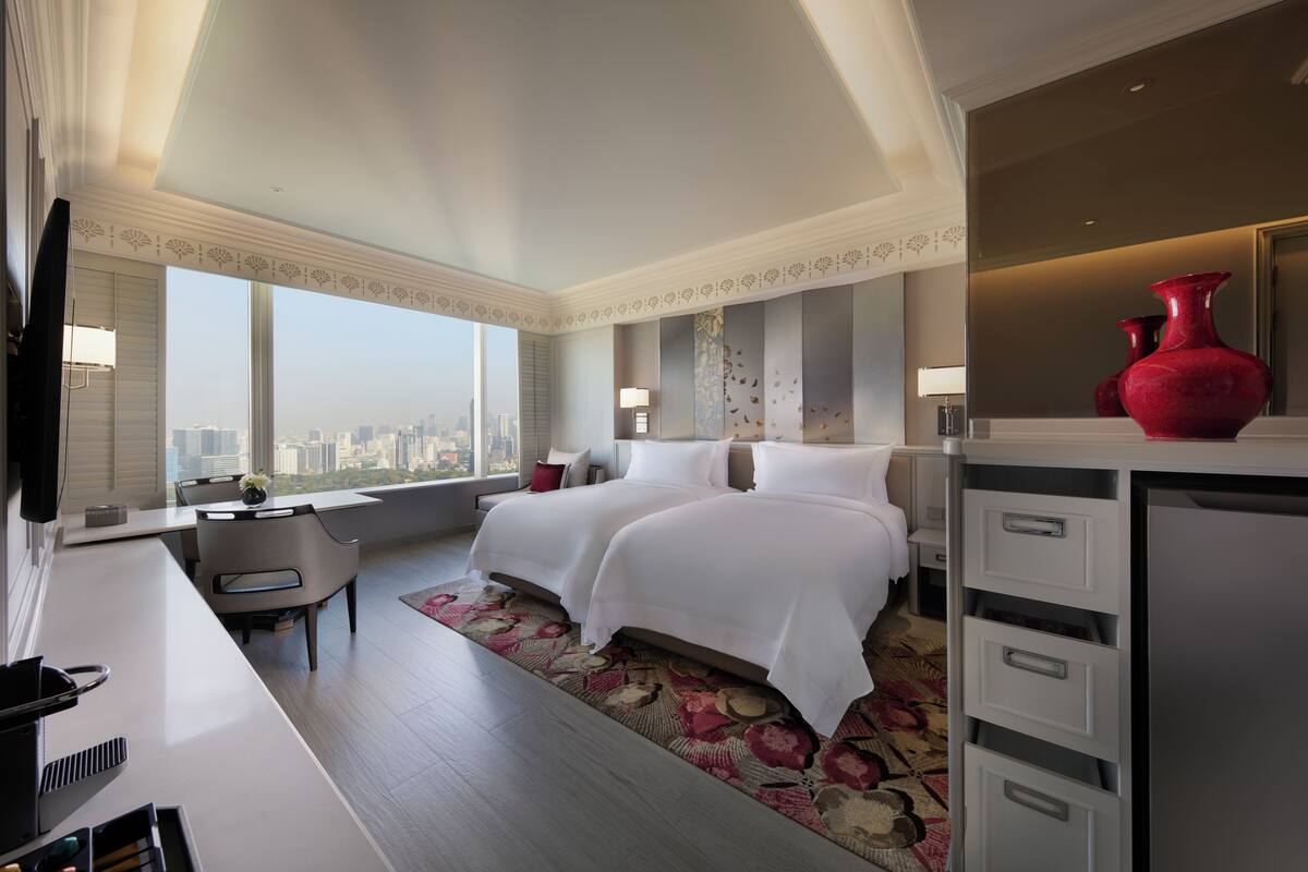Une chambre d’hôtel moderne dotée d’un grand lit, d’un bureau et offrant une vue sur le panorama urbain.