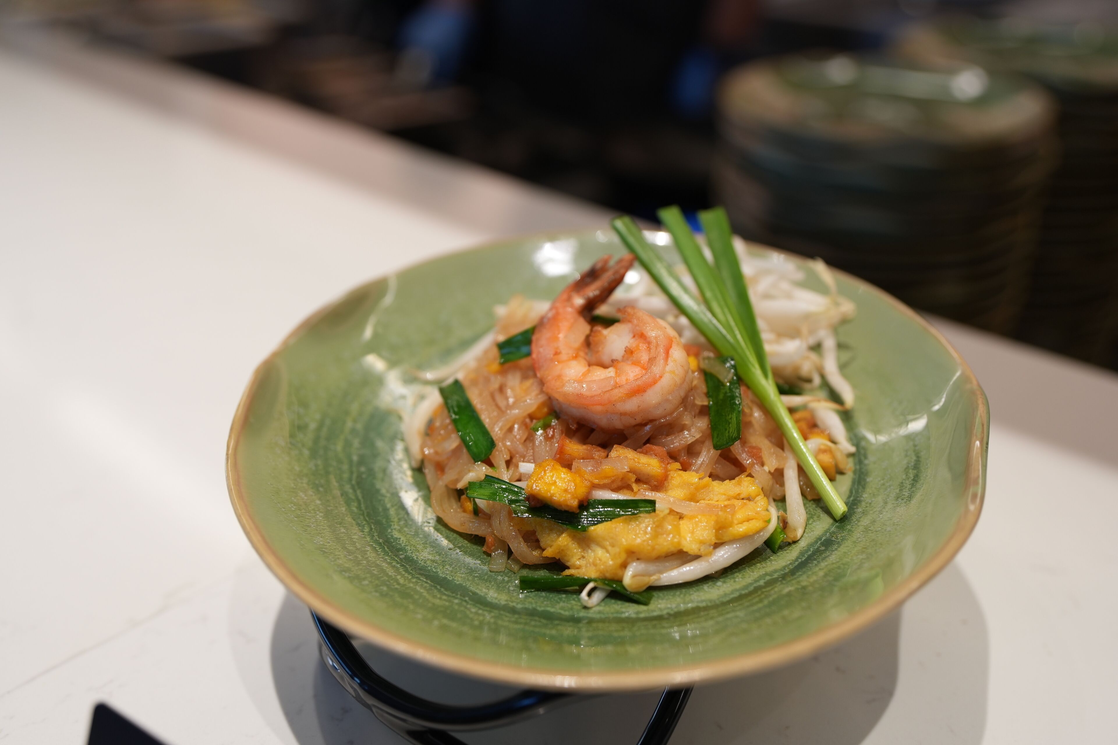 A bowl of noodles with shrimp and vegetables.
