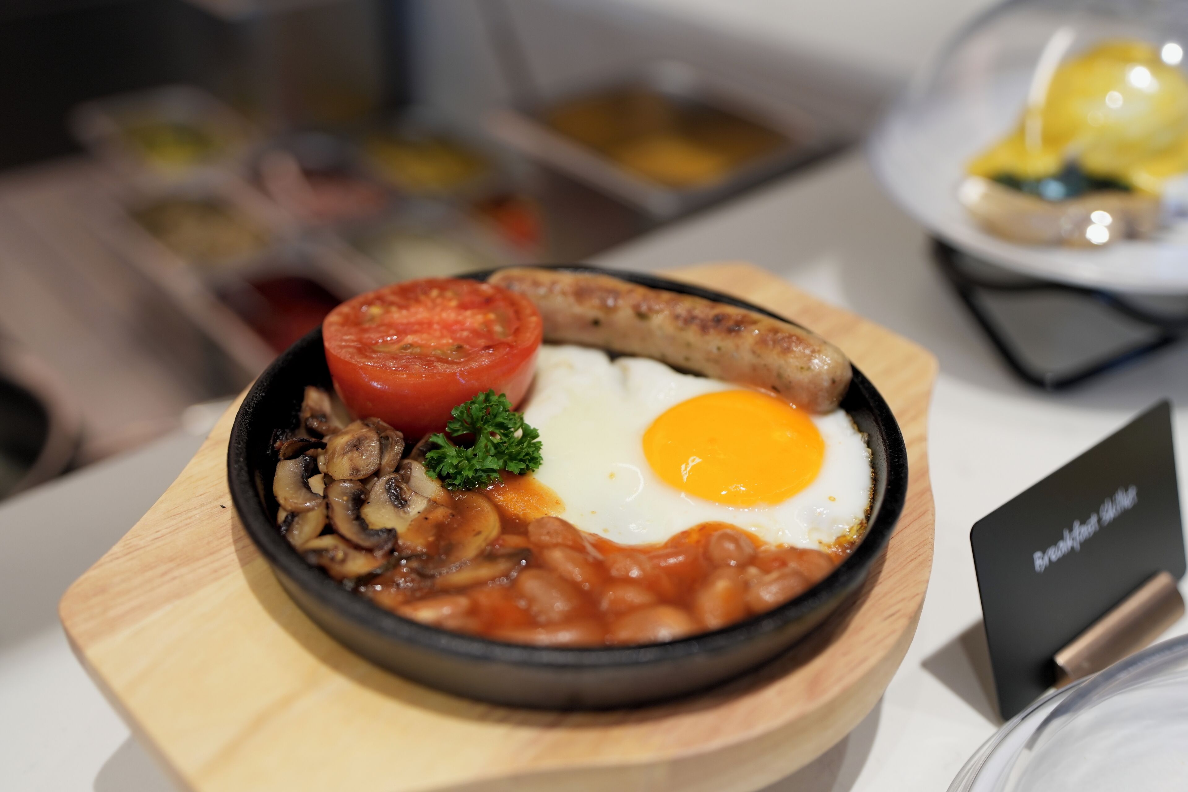 A breakfast plate with eggs, sausage, mushrooms, tomatoes, and beans.