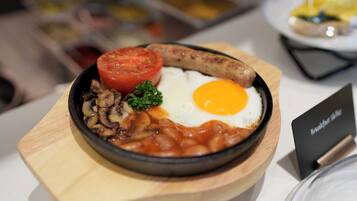 A breakfast plate with eggs, sausage, mushrooms, tomatoes, and beans.