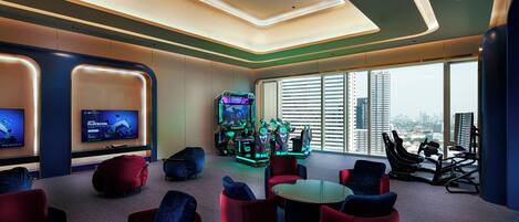 Een moderne lounge met comfortabele zitplaatsen, een groot scherm waarop een spel wordt vertoond en uitzicht op de stads skyline.