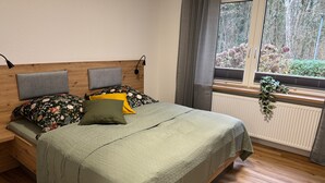 A bed with a headboard, a window with a view of trees, and a radiator. - Apartment 'Ahlers' with Shared Terrace, Private Garden and Wi-Fi (Edewecht)
