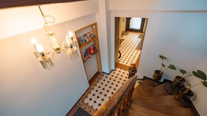 Una escalera con piso a cuadros, barandilla de madera y un candelabro.