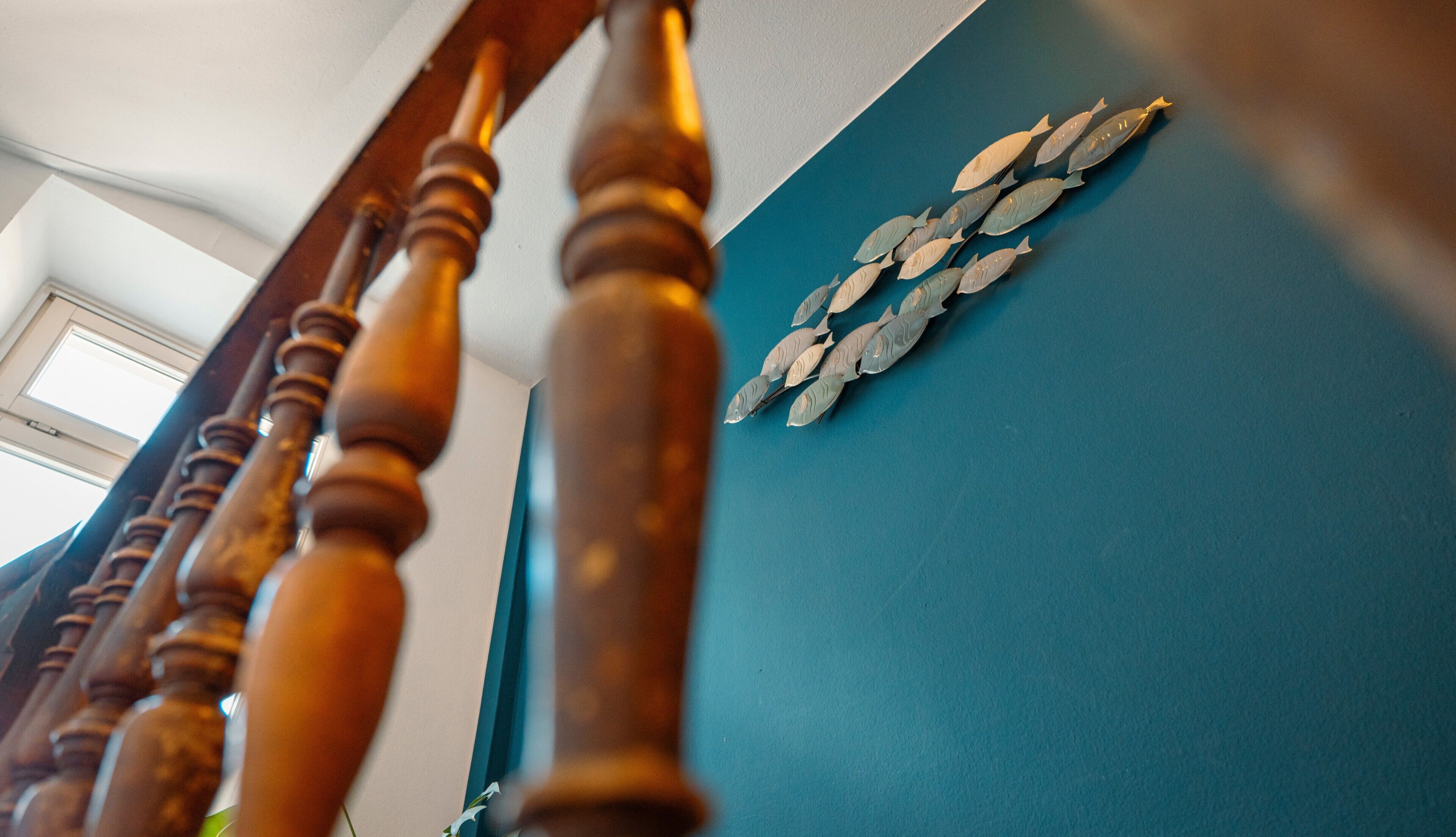 A staircase with wooden balusters and a blue wall with a decorative fish wall art.