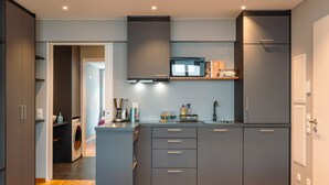 A modern kitchen with grey cabinets, a microwave, and a built-in washing machine.