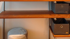 A wall-mounted circular mirror with a distressed finish, a wooden shelf with metal brackets, and a storage unit with baskets.