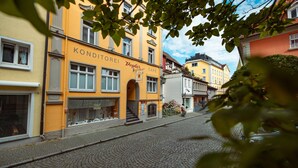 A cobblestone street lined with buildings, one with a sign reading 'KONDITOREI Vogler Café.'