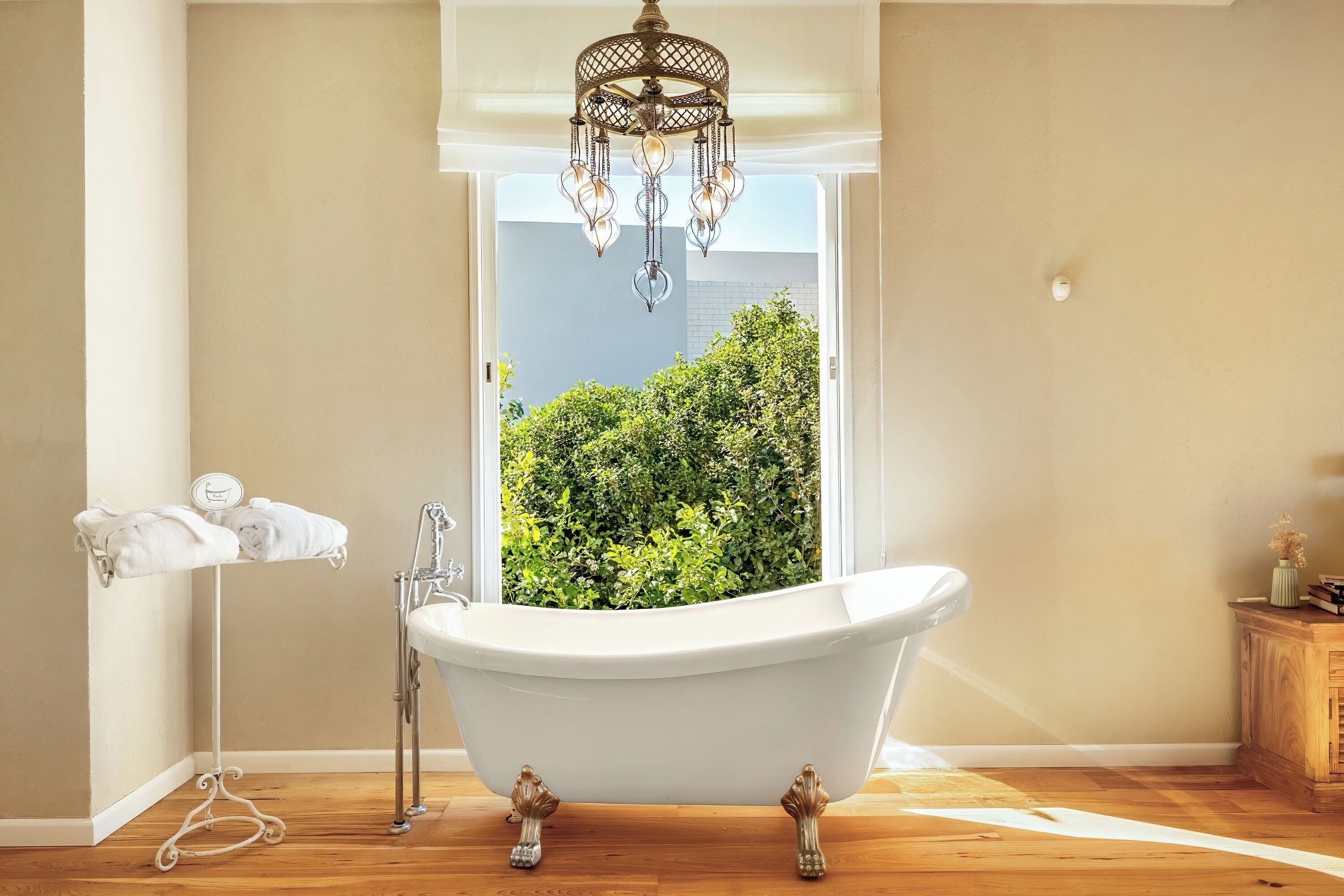 A bathroom with a freestanding bathtub, a towel rack, a sink, and a chandelier.