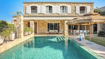 Un edificio de piedra de dos pisos con una piscina delantera.