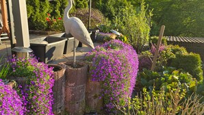 A garden with a bird sculpture, a pergola, and various plants. - Apartment 'Osterwiese' with Private Terrace, Private Garden and Wi-Fi (Weilburg)