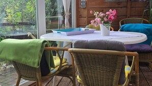 A wooden cabin with a table, chairs, and a window overlooking greenery. - Apartment 'Osterwiese' with Private Terrace, Private Garden and Wi-Fi (Weilburg)