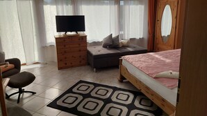 A bedroom with a bed, a TV on a wooden dresser, a chair, and a desk. - Apartment 'Osterwiese' with Private Terrace, Private Garden and Wi-Fi (Weilburg)