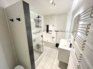 A modern bathroom with a glass shower enclosure, a bathtub, a toilet, and a white vanity with a towel rack. - Apartment 'An-der-Aschaffaue' with Balcony and Wi-Fi (Aschaffenburg)