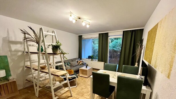 Un salon comprenant un canapé, une table à manger, des chaises, une échelle et un téléviseur.