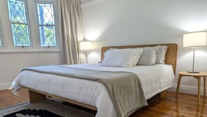 Ein Schlafzimmer mit einem Holzbett, zwei Nachttischlampen, einem Fenster mit Vorhängen und einem Teppich.