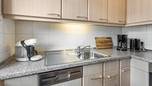 Eine Küche mit hellen Holzschränken, einer Granitarbeitsplatte, einer Kaffeemaschine, einem Toaster und einem Geschirrspüler.