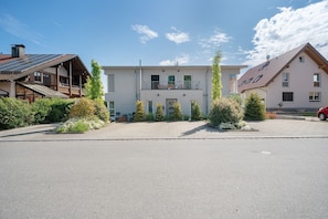 A modern building with a flat roof, large windows, and a paved driveway.