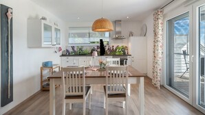 Uma cozinha moderna com área de refeições, grandes janelas e vista para o exterior.