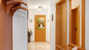 A hallway with wooden doors, a wooden bench, a mirror, and a framed picture on the wall.
